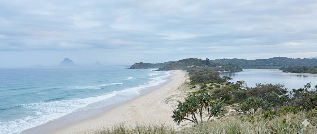 A wide South East Queensland coastal landscape — soft sky, muted blues, headlands in the distance
